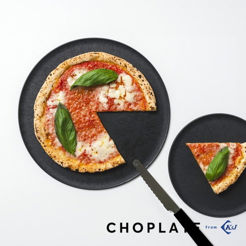 黑色的CHOPLATE兩用砧板盤，盤中盛放著一個瑪格麗特披薩，披薩已切開，旁邊有一小塊披薩和一把餐刀，盤子呈現圓形，質感粗糙。