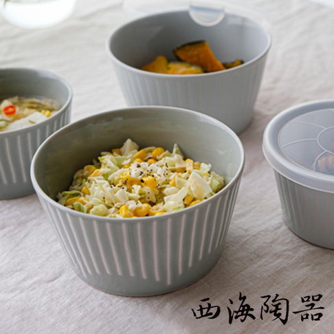 灰藍色波佐見燒花FUWARI微波小碗，碗身帶有細緻的垂直壓紋，其中一個碗內盛有玉米粒、高麗菜絲及黑胡椒拌成的沙拉，另一個碗盛有南瓜塊，背景為淺色布料。