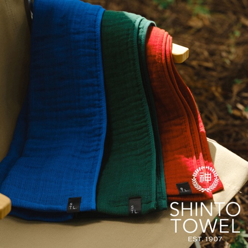 三條顏色分別為藍色、綠色和紅色的柔軟隨身暖毯，以層疊方式掛在椅子上，材質呈現細緻紋理。