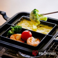 黑色直火專用熱壓三明治夾烤盤，內有兩個獨立烤槽，烤槽內裝有融化的起司、青花菜、小番茄和蝦子。