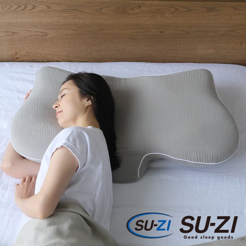 灰色側睡止鼾枕，具有凹槽設計，柔軟的織物表面，白色滾邊，一位女性正側臥於枕上。