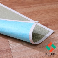 藺草抗菌除臭枕墊，一側為淺綠色藺草編織材質，另一側為淺藍色無紡布材質，邊緣有白色布條包邊，平鋪於木質地板上。