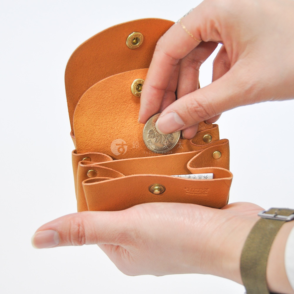 職人手作皮革三層收納零錢包，展示棕褐色皮革材質，有三個隔層，一個硬幣正被放入其中。