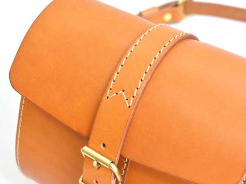 職人手作皮革皮扣單肩包，選用天然棕色皮革製作，帶有精緻的縫線細節，並配有黃銅金屬皮扣，風格簡約實用。