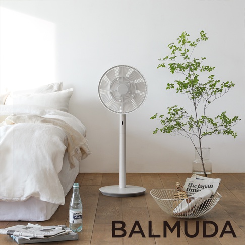 The GreenFan 風扇，白色，立式設計，圓形扇葉網罩，帶有纖細的直立支架和圓形底座，置於臥室環境中。