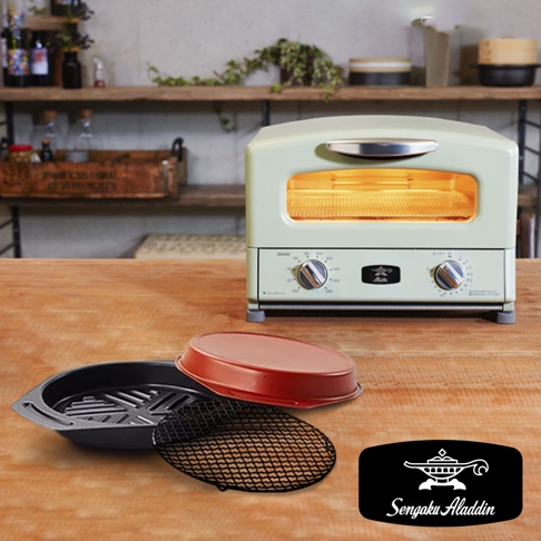 淺綠色復古多用途烤箱，配有銀色把手和兩個旋鈕，內部烤網發熱。前方桌面擺放著黑色烤盤、紅色烤蓋和黑色網架。