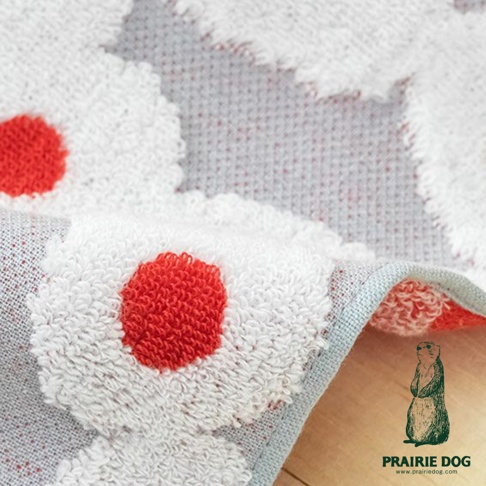 觸發條件：文字字數≤50字或以視覺為主 輸出格式：純文字描述 GuuGuu 飽足食光今治提花刺繡方巾，白色花朵圖案搭配紅色圓點，材質柔軟，角落有品牌標誌。