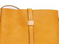 職人手作皮革散步直式單肩包 (CP-3)，以柔軟的黃褐色皮革製成，簡潔的設計，正面有皮革束帶與固定扣，肩帶亦為皮革材質。