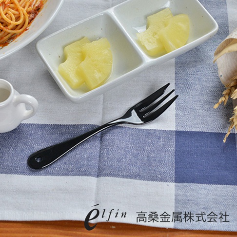 一支日製黑色琺瑯水果甜點叉，有三叉，叉柄末端有圓孔，置於藍白格紋布上。