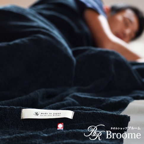深藍色 karoyaka 今治毛巾被，觸感柔軟，展現日本職人精湛工藝，細緻紋理清晰可見，標籤標示「made in Japan」及品牌 Logo，體現產品的高品質。