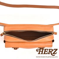 職人手作皮革騎士隨身斜背包，淺棕色皮革材質，設有拉鍊開口，可見內部空間，配有同色系皮革背帶。