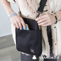 一位身穿米白色蓬鬆背心和條紋上衣的女子，斜揹著一個黑色直式口金斜背包，並將一個藍色錢包放入包包前方的外袋中。