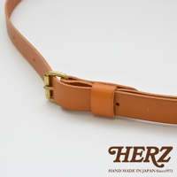 職人手作皮革單肩包的細節，展現厚實的棕褐色皮革材質，搭配復古黃銅調節扣，整體呈現經典風格。