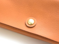 職人手作皮革旅行用長夾，採用細緻紋理的淺棕色真皮皮革，搭配圓形黃銅按扣，展現簡約質感。