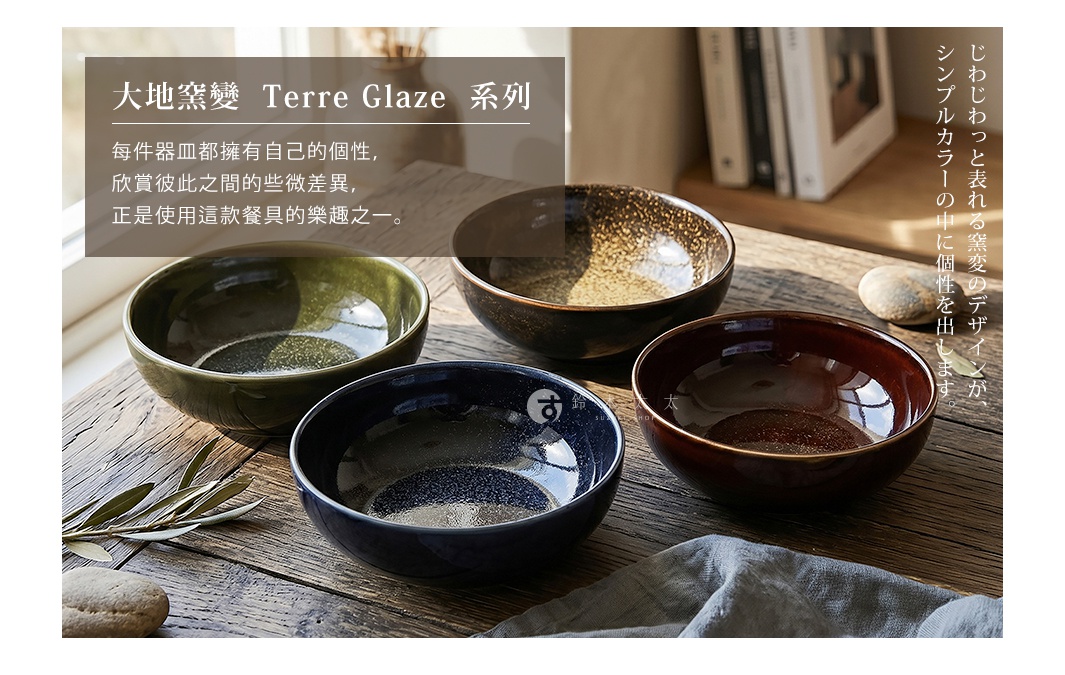 四個不同色彩與釉面紋理的寬口陶瓷碗，分別呈現墨綠、金黃、深藍與深褐色，擺放在木質桌面上，並飾以橄欖葉與圓潤石塊，體現日式窯變工藝的自然美感與獨特設計。