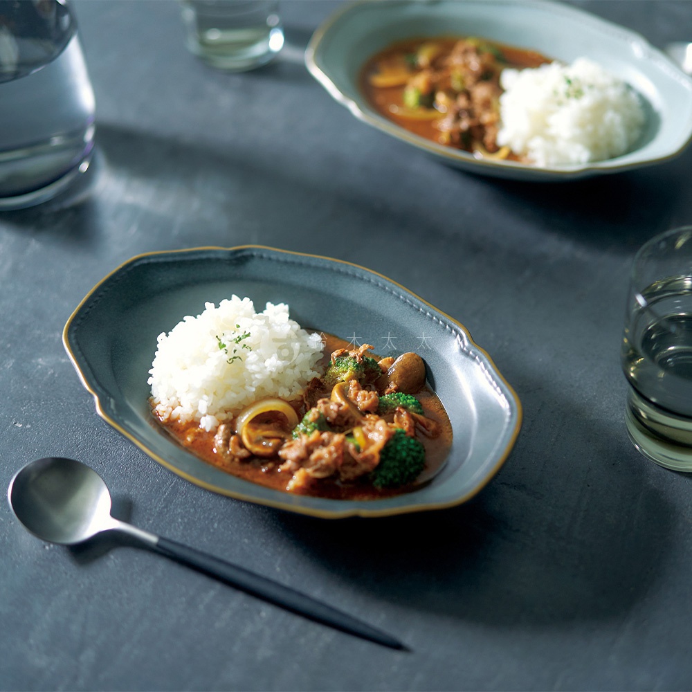 Aito Stitch 美濃燒金彩浮雕橢圓深盤盛著咖哩飯，旁邊放著一把餐勺。