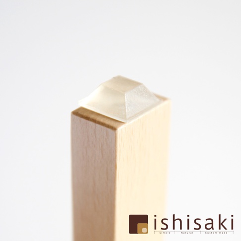 淺色木頭製成的方形柱體頂端，裝有一個透明的錐形塑膠墊。