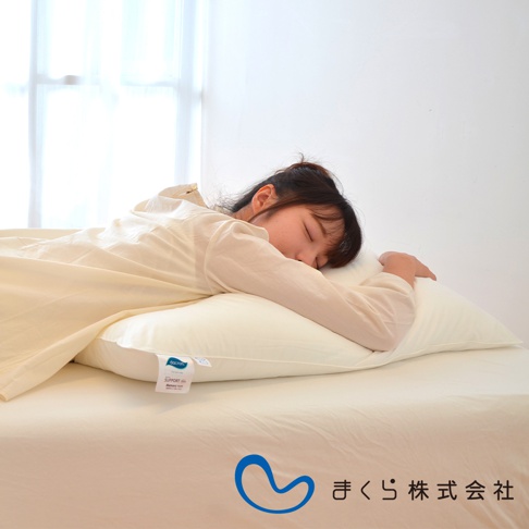 一名女子側臥在米白色方枕上，枕頭置於米白色床單上，枕頭上有產品標籤。