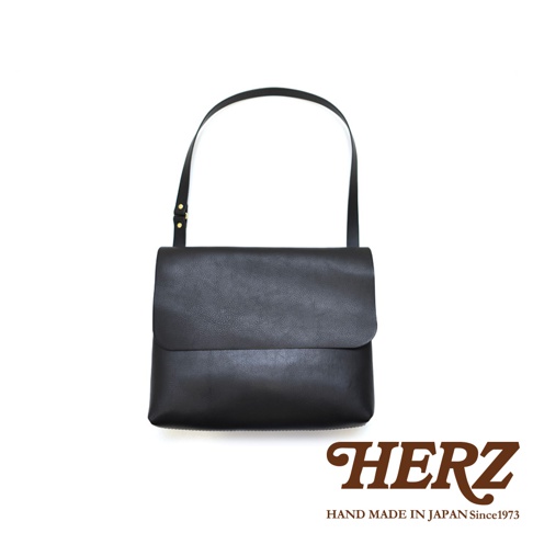 職人手作經典郵差包，黑色皮革材質，包身簡潔，翻蓋設計，配有可調節肩帶。