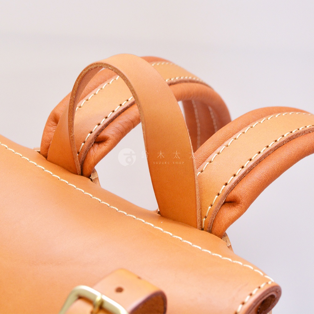 職人手作皮革復古風旅行後背包 R-65，特寫展示其縫線精緻、皮革材質的提把與包身細節，呈現自然的皮革色澤。