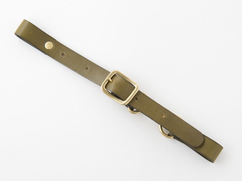 橄欖綠皮革製成的背包胸前扣帶，寬度約3公分，配有黃銅色金屬扣環、鉚釘及兩個D型環。