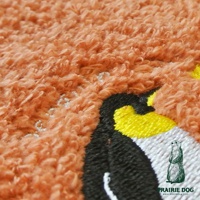 橘色精梳棉方巾，帶有企鵝刺繡圖案，材質柔軟。