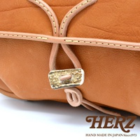 棕色皮革郵差包，採用鹿角扣環與皮革繩設計，搭配手工縫線，展現職人質感。