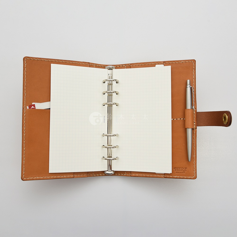 職人手作皮革手帳/記事本書套 KB-7 (淺棕色) ，打開的狀態，內部為網格筆記紙，左側有卡片夾層，右側有筆插，附一支銀色金屬筆。
