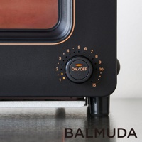 黑色蒸氣烤麵包機，設有黑色圓形旋鈕，上面有「ON/OFF」字樣及橙色指示燈，旋鈕周圍有數字刻度，顯示從 1 到 15 的時間設定。烤麵包機外部為霧面黑色，邊緣有橙色飾條。