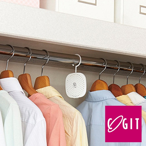 衣櫃掛鉤上懸掛著一個白色方形的除臭防霉貼片盒，盒身有多個小孔，旁邊掛著幾件不同顏色的襯衫。