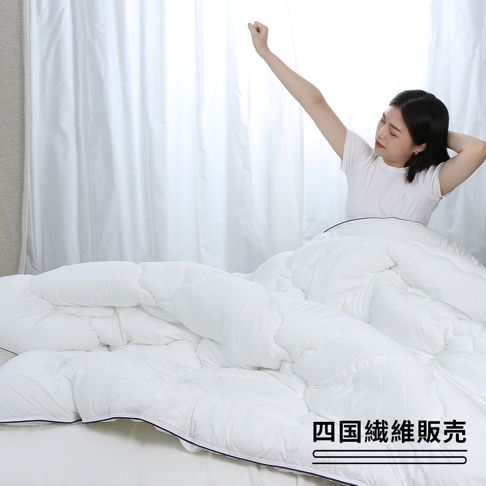 白色雙人SOFAIR無重力空氣被，中棉填充，被面為絎縫設計，帶有深藍色滾邊，一位女性坐在床上，伸展身體。