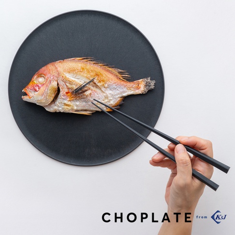 以黑色盤子盛裝的烤魚，一雙黑色筷子正夾著魚，盤子下方印有 CHOPLATE from KSJ 字樣