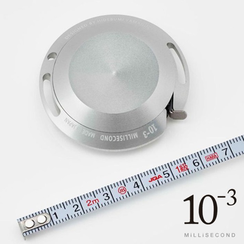 銀色鋁製捲尺，2公尺長，附有刻度，包含「JIS」、「JQA」等標誌，捲尺外殼為圓形設計，表面刻有「DESIGNED BY HIDEBUMI YAMAGUCHI」、「MILLisecond MADE IN JAPAN」、「10-3」等字樣。