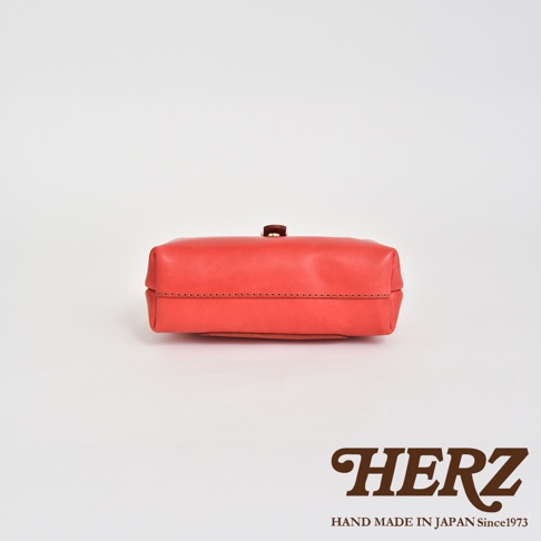 橘紅色軟皮迷你杜勒斯包，以職人手作皮革製成，包身簡約，頂部有金色旋轉鎖扣，線條清晰，材質柔軟。