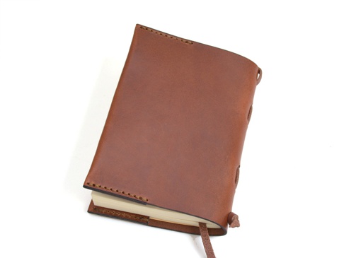 職人手作皮革附繩書套，採用棕色皮革製成，側邊以皮革繩編織固定，並附有皮革書籤帶。