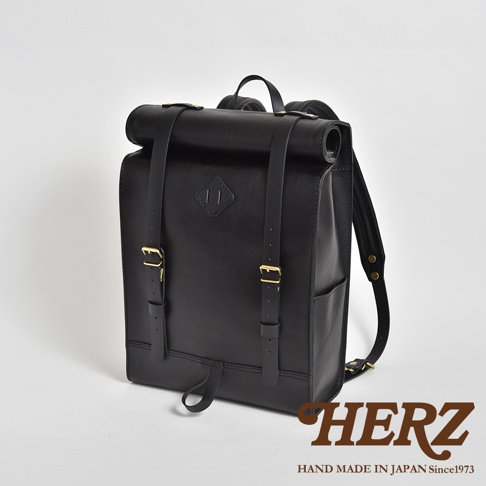 黑色皮革製成的大容量後背包，捲口設計，配有兩條可調節肩帶和金色扣環，前方有菱形壓紋。