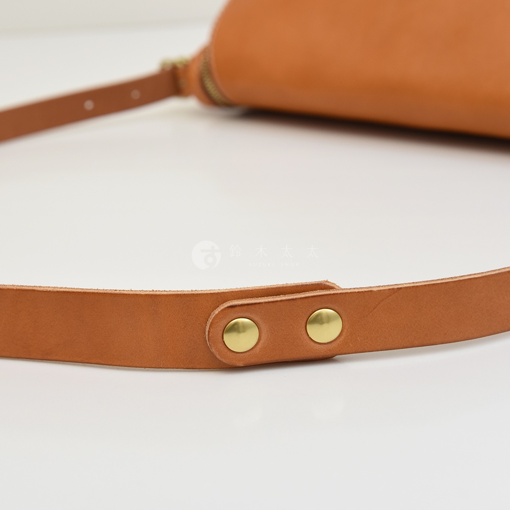 皮革包帶特寫，上有兩個金色铆釘