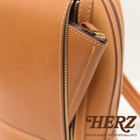 棕褐色皮革立體商務後背包，特寫拉鍊細節，搭配金色拉鍊和縫線，展現職人手作質感。