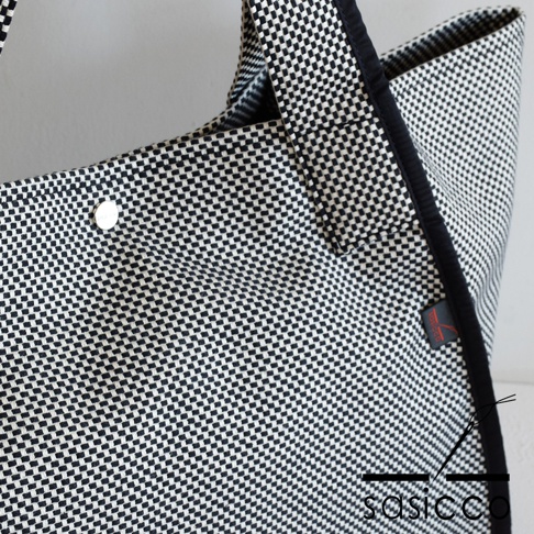 三河木綿刺子織可變形大容量托特包，黑白格紋織紋，附有銀色按扣及黑色滾邊，右側有紅色品牌標籤。