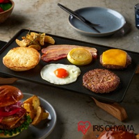 黑色 IHU-A10-B 電烤盤上擺放著豐富的早餐食材，包括煎蛋、培根、洋蔥圈、漢堡肉排、起司漢堡肉排、烤麵包和薯條。