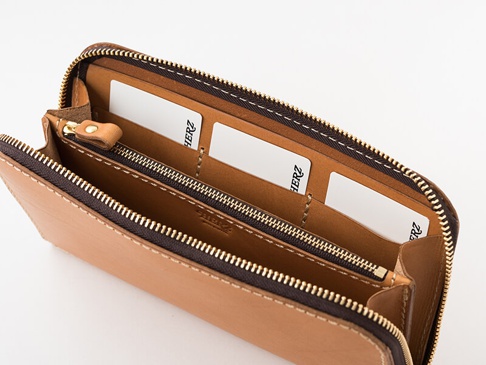 職人手作皮革大容量拉鍊長夾，淺棕色牛皮材質，拉鍊為深棕色。內部分隔清晰，可見多個卡槽，部分卡槽內插有白色卡片。整體風格簡約實用。