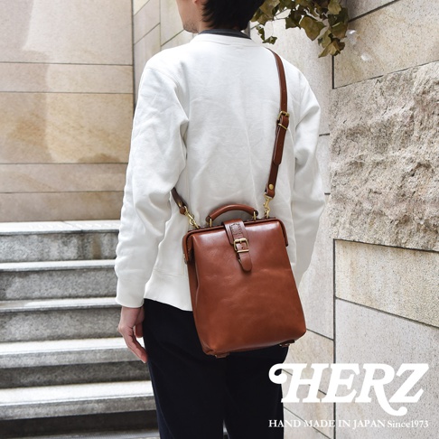 棕色皮革迷你軟皮杜勒斯包，配有可調節肩帶和金色搭扣。