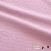 粉色織物材質，表面有細小的點狀紋理，呈現細緻的織紋感，布料有自然的褶皺。