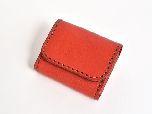 橘紅色皮革雙折收納零錢包，手工縫製，簡約設計。