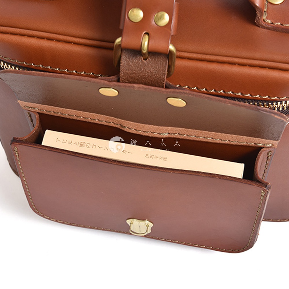 日本HERZ 職人手作皮革厚實相機包 N-8，近拍特寫，展示包包內部的卡槽，裡面放著一張印有日文和品牌名的卡片。