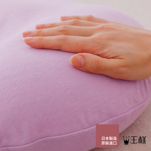 女人的手輕柔觸碰淺紫色織物枕套，材質柔軟，細節紋理清晰可見。