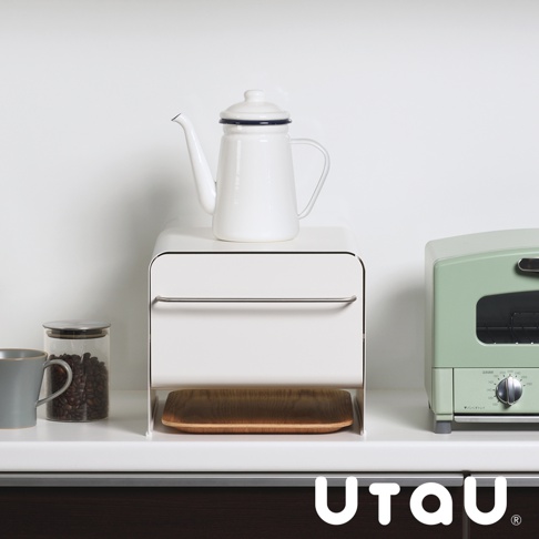 抽屜式多功能收納櫃，白色，帶有一個金屬拉手，下方有一個木質托盤，旁邊有灰色馬克杯和裝有咖啡豆的玻璃罐，以及一台綠色烤麵包機。