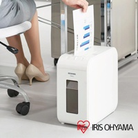 白色IRIS OHYAMA P6HCS極細碎紙機，上方進紙口正在被放入一份帶有藍色長條圖表的紙張。碎紙機前方有一個較小的觀察窗，底部有四個白色圓形腳墊。