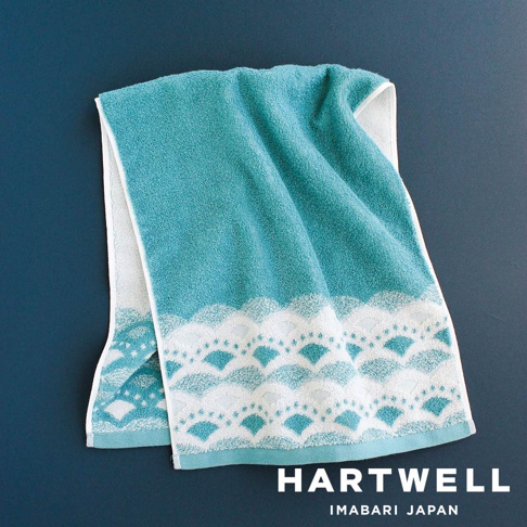 一條水藍色毛巾，帶有傳統日式扇形紋樣和波浪邊飾，材質為柔軟的棉織品。