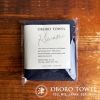 深藍色細纖毛巾，觸感極佳，包裝精美，正面標示「OBORO TOWEL Kiwami」，強調百年工藝與極致柔軟，材質為100%純棉，日本製造。